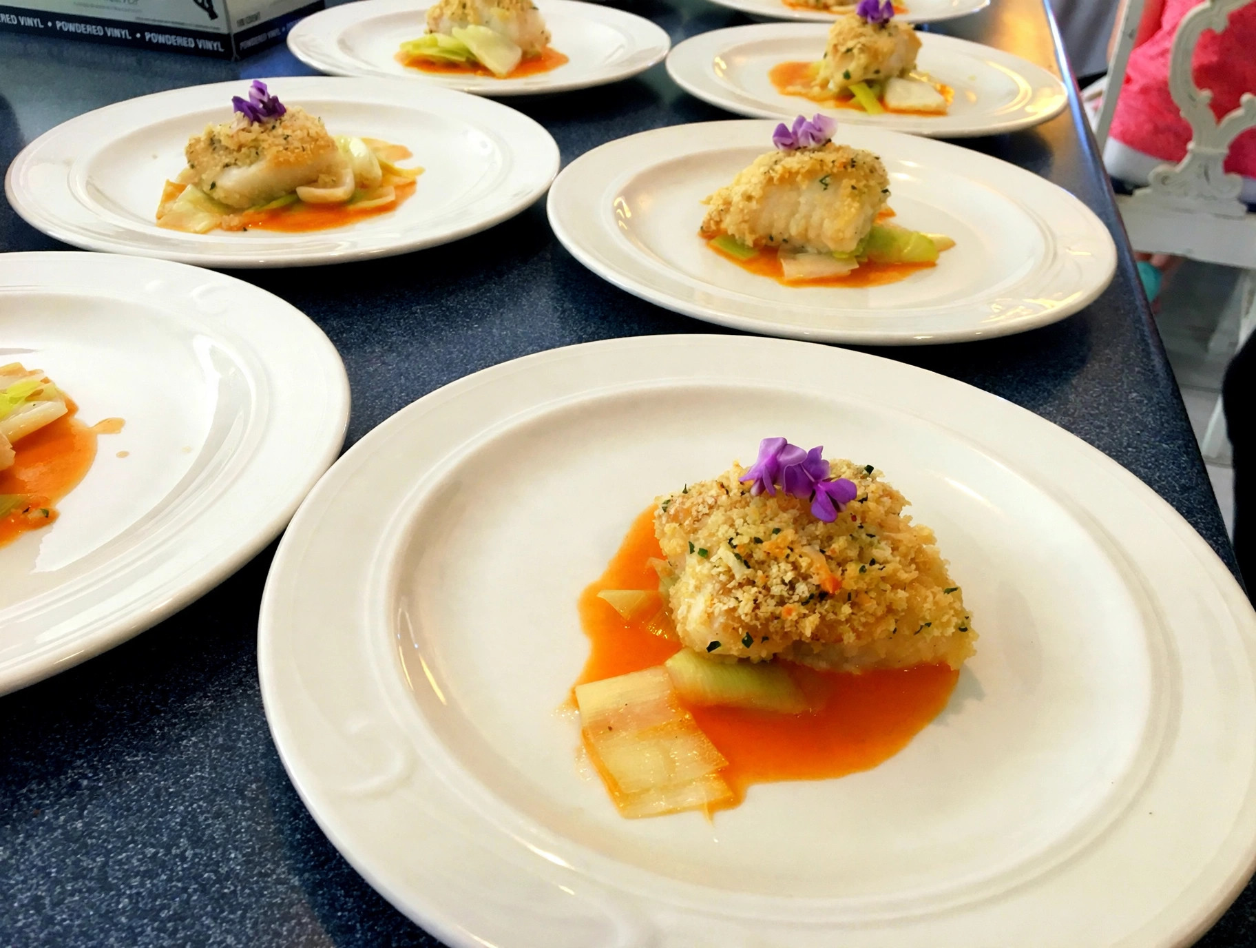 Herb-crusted fish with edible flowers and citrus sauce