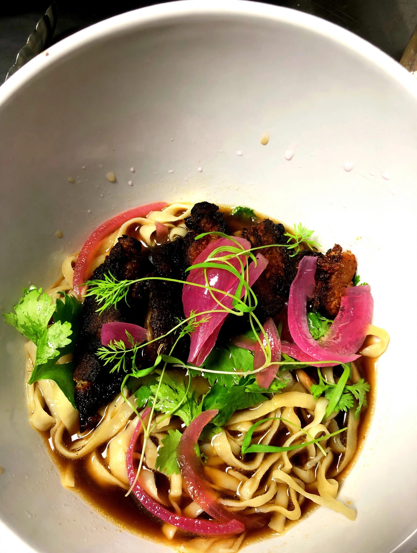 Crispy pork belly noodle bowl with pickled onions