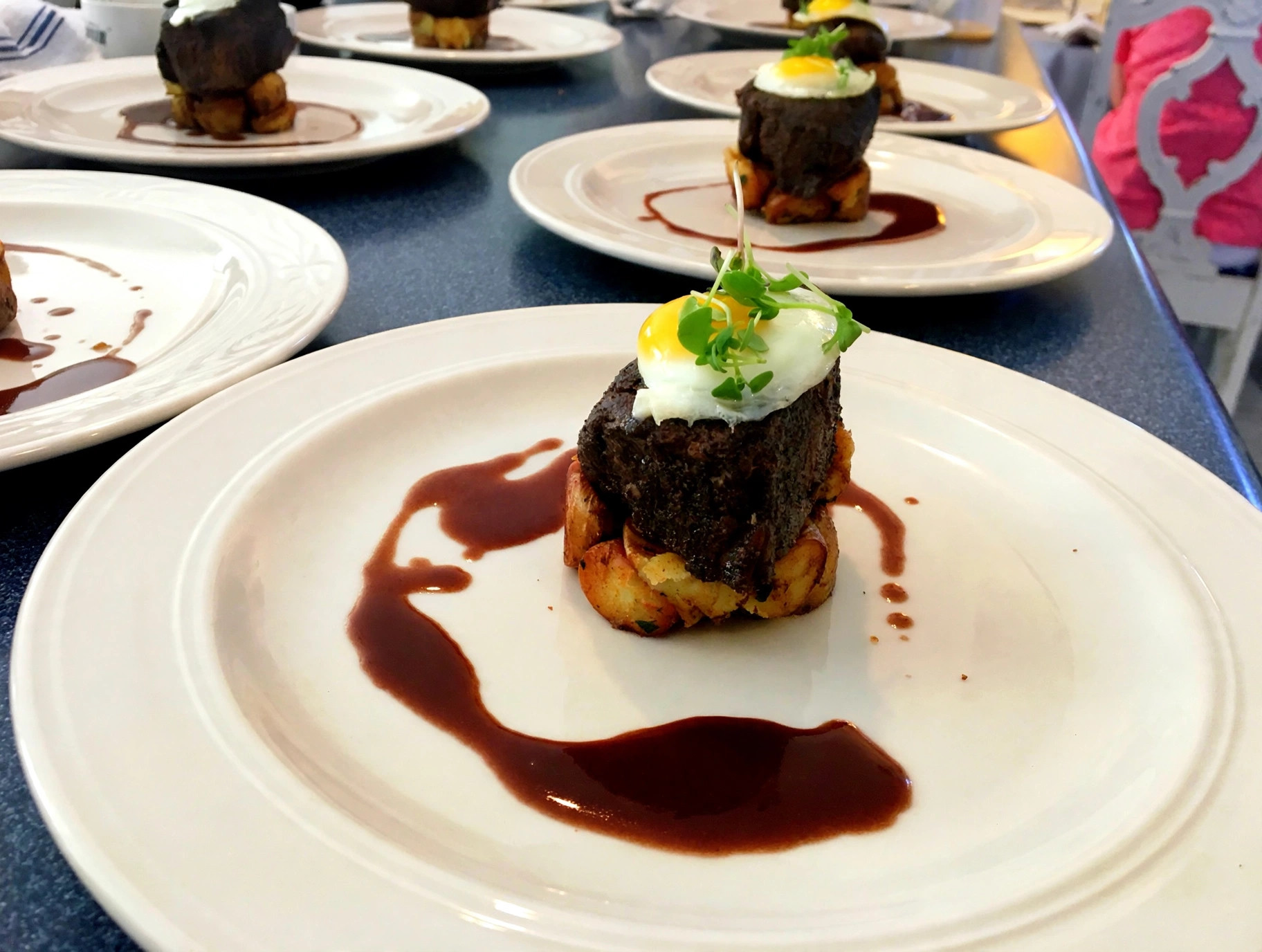 Beef tenderloin with fried egg and microgreens over potatoes